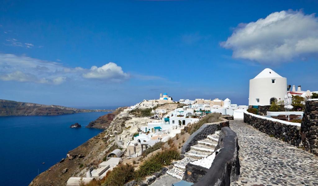 a view of a island with a white building on a hill at Elegant Santorini House 1 Bedroom Villa Windswept House Amazing Caldera View & Outdoor Hot Tub Oia in Thólos