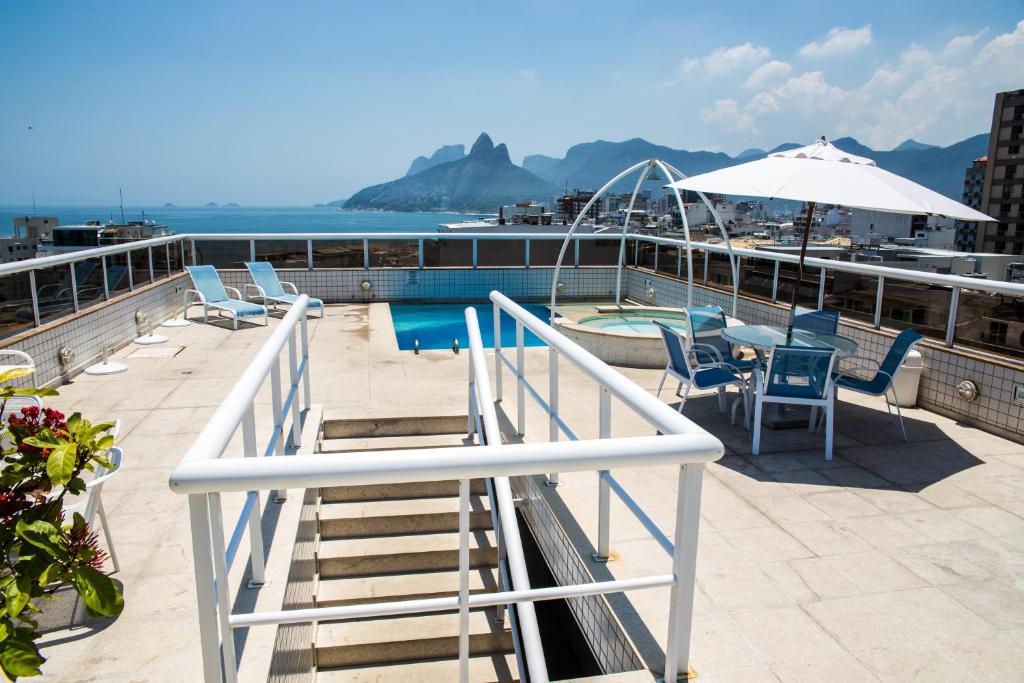 a balcony with chairs and a table and an umbrella at Atlantis Copacabana Hotel in Rio de Janeiro