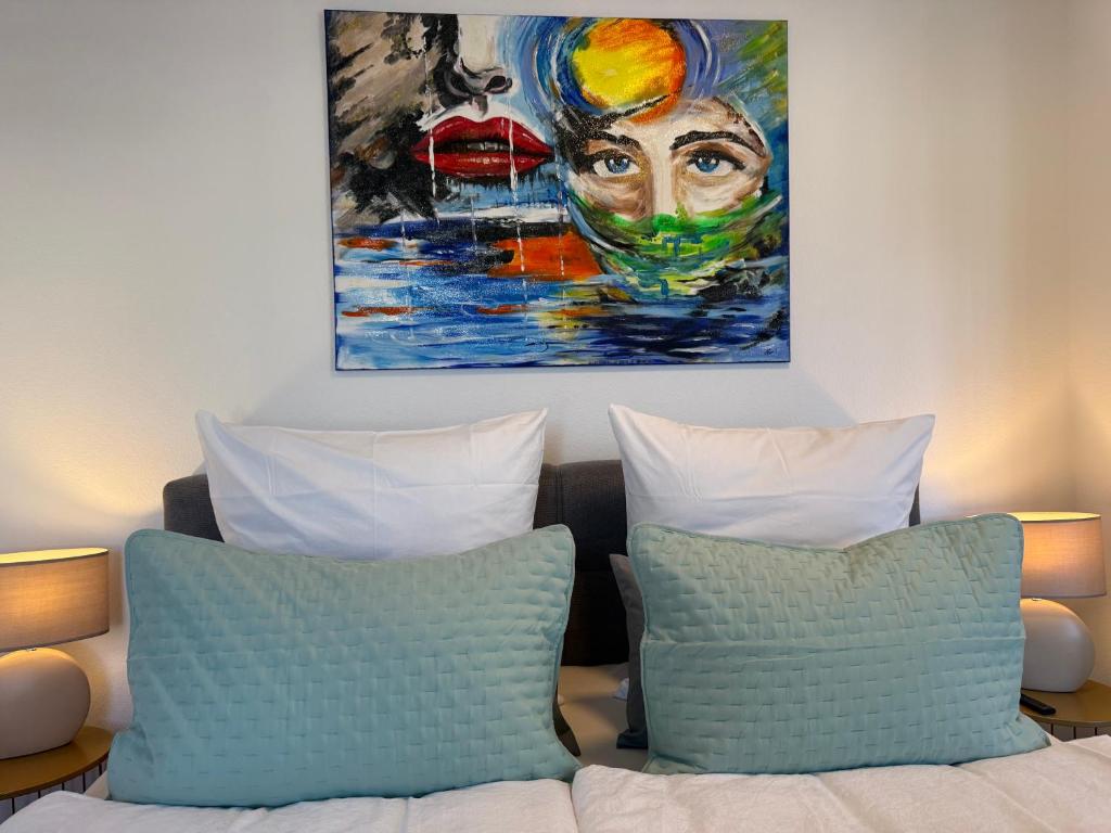 a painting above two pillows on a bed at Gemütliches Apartment nähe HBF-City--Lift in Hannover
