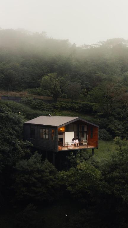 a house on a hill with two people sitting on a porch at Casas Jaguar in Monteverde Costa Rica