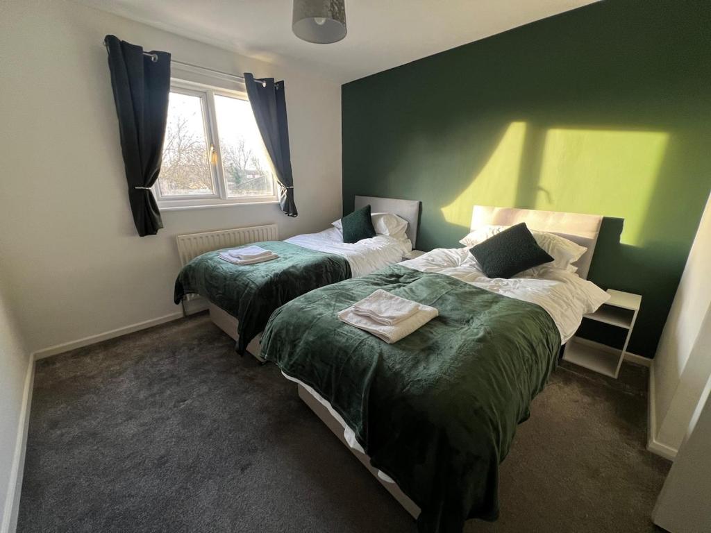 2 łóżka w pokoju z zielonymi ścianami w obiekcie Harkness Suite - Contractors w mieście Cheshunt
