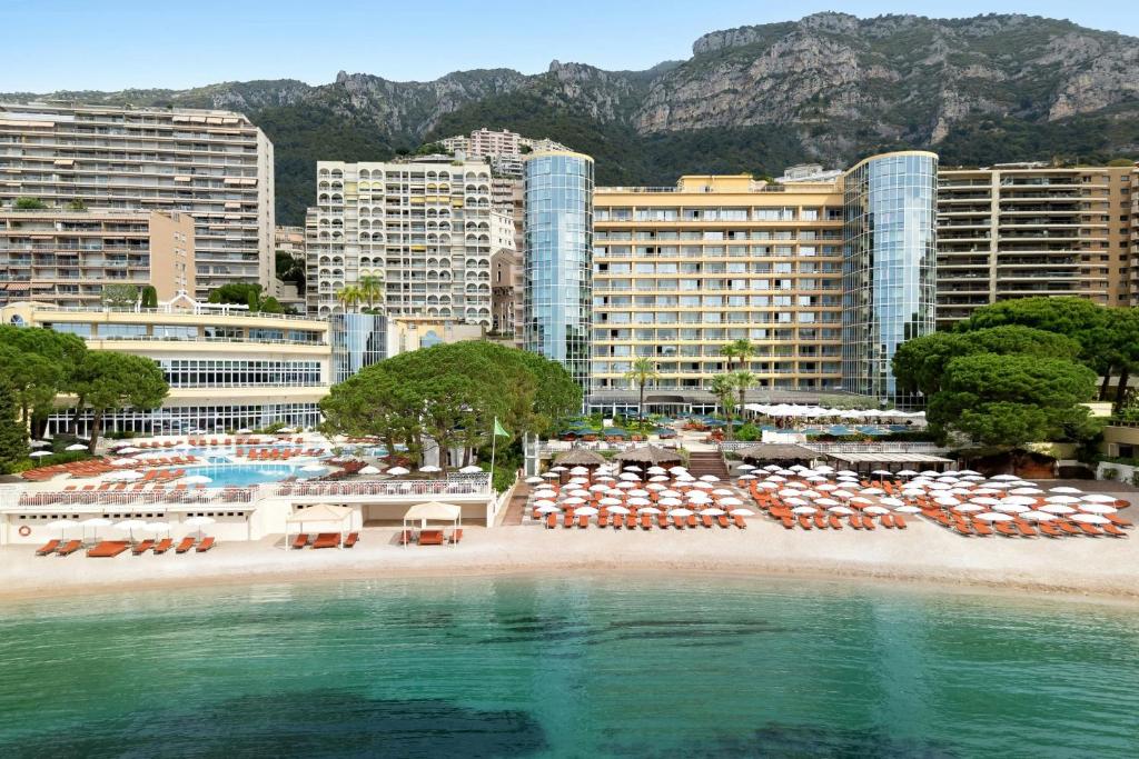 a beach with chairs and umbrellas in front of buildings at Le Méridien Beach Plaza in Monte Carlo
