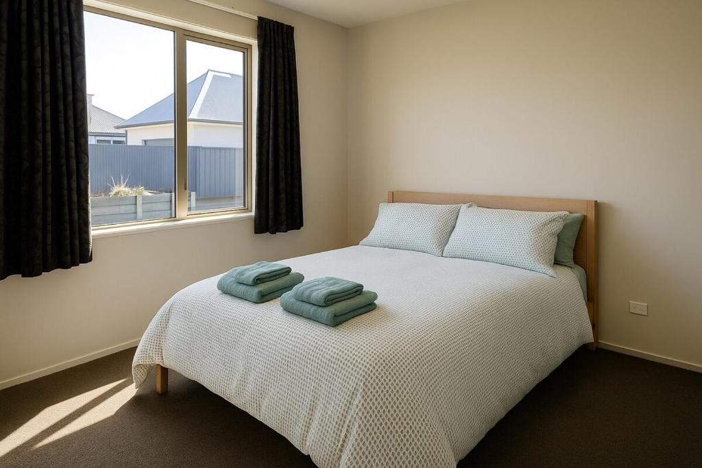 a bedroom with a bed with two towels on it at West Meadows Escape, Lake & Slopes Minutes Away in Wanaka