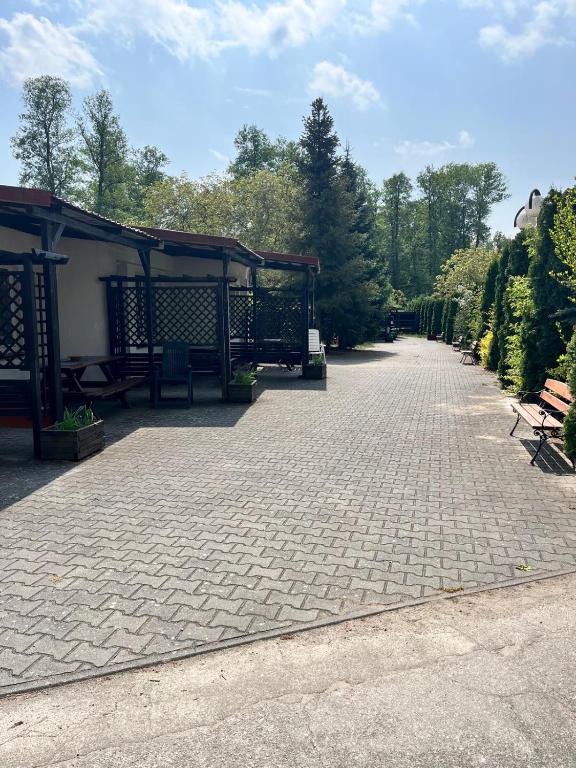 a walkway with benches and a pavilion in a park at Rusałka Domki Rodzinne in Rudno