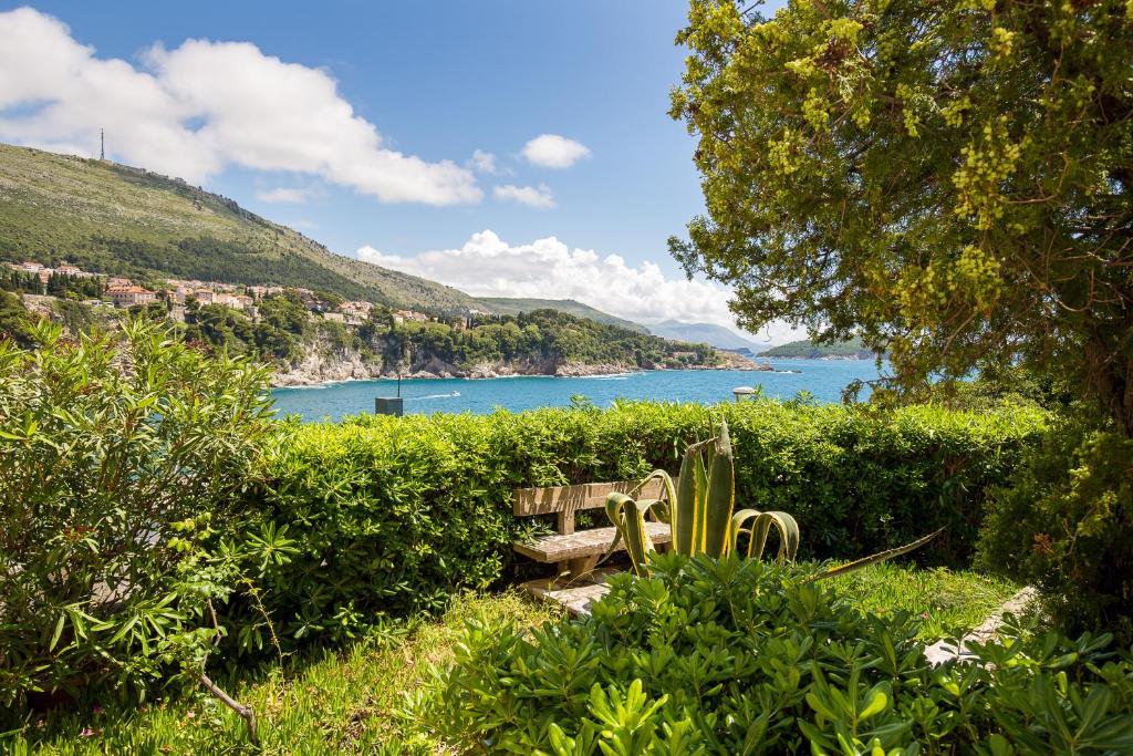 un banco sentado en el césped junto a un cuerpo de agua en Guest House Steel, en Dubrovnik