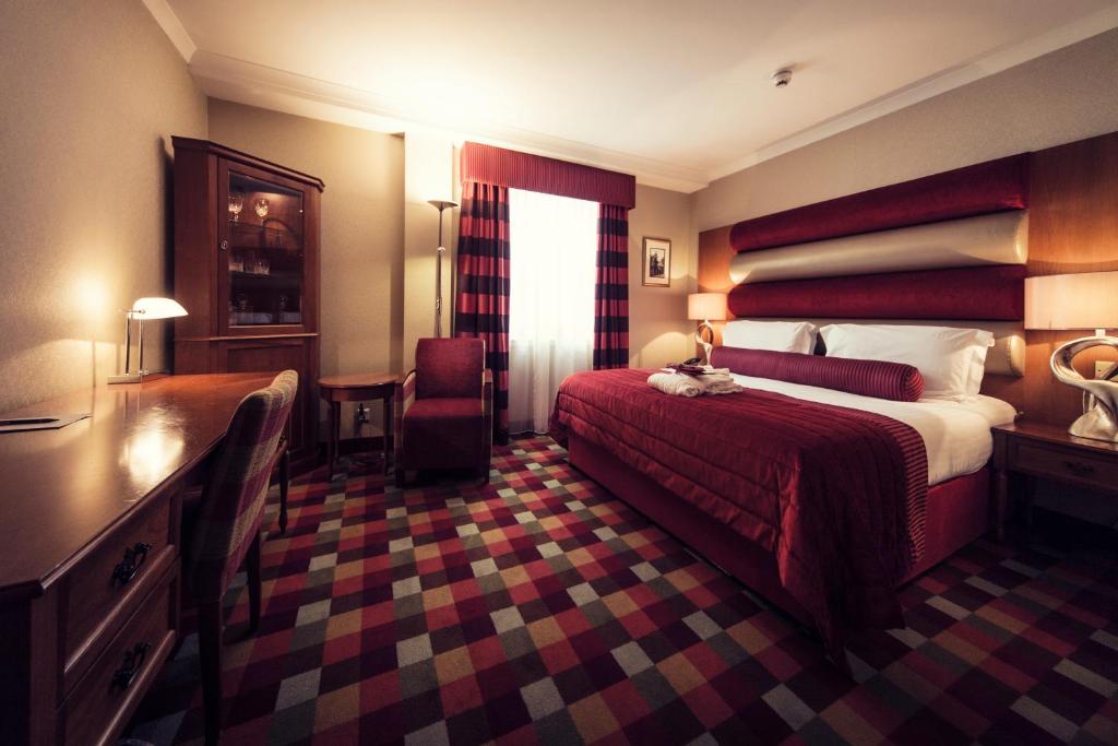 a hotel room with a large bed and a desk at Carlton George Hotel in Glasgow