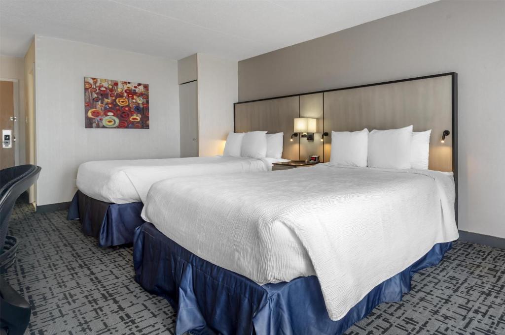 a large white bed in a hotel room at Best Western Hotel Brossard in Brossard