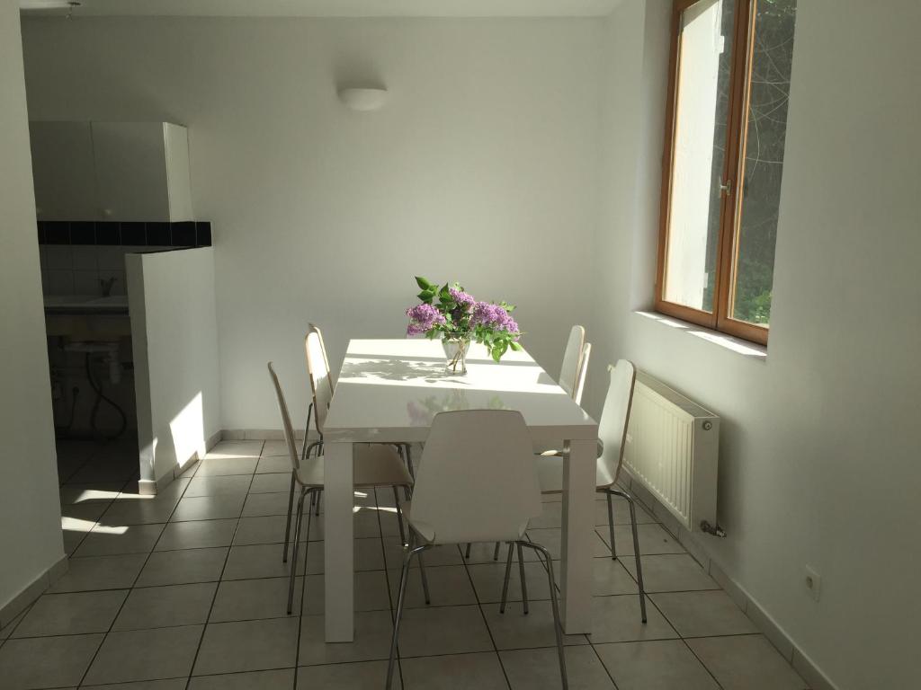 a white dining room with a white table and chairs at Maison Lyon in Irigny