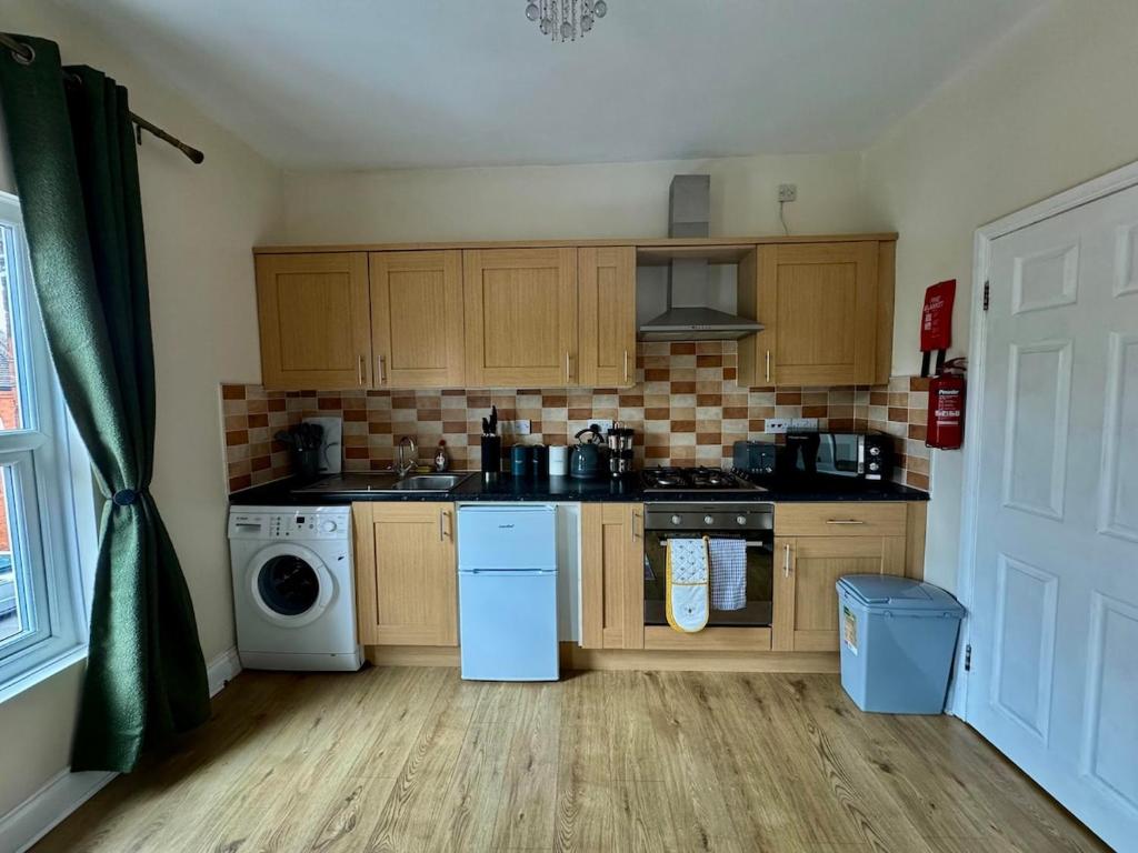 a kitchen with wooden cabinets and a washer and dryer at Stylish apartment in the City Centre in Spinney Hill