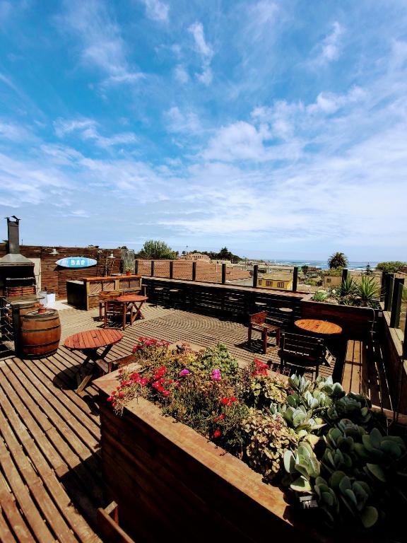 a deck with a table and chairs and flowers at LÖF Hostal in Pichilemu