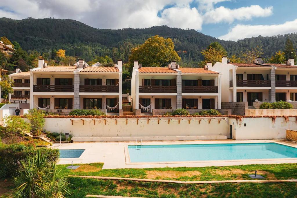 an external view of a large building with a swimming pool at IKIGAI Gerês - A Lake Edition in Geres