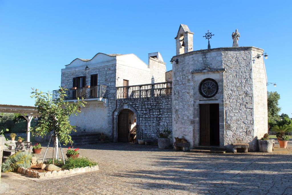 an old stone building with a clock on it at Masseria Tolla in Ostuni