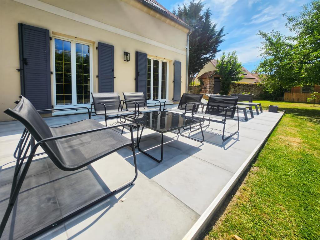 a patio with chairs and a table on it at Maison Cosy Campagne, Spacieuse, Terrasse in Le Plessis-Feu-Aussoux