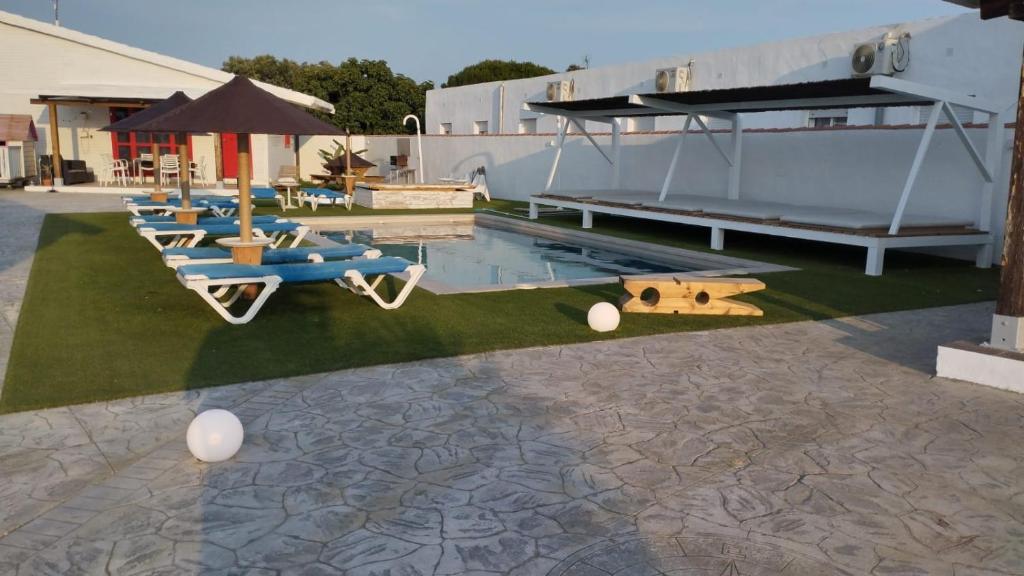 Una piscina con tumbonas y un grupo de tablas de surf. en La pinza verde, en Cádiz