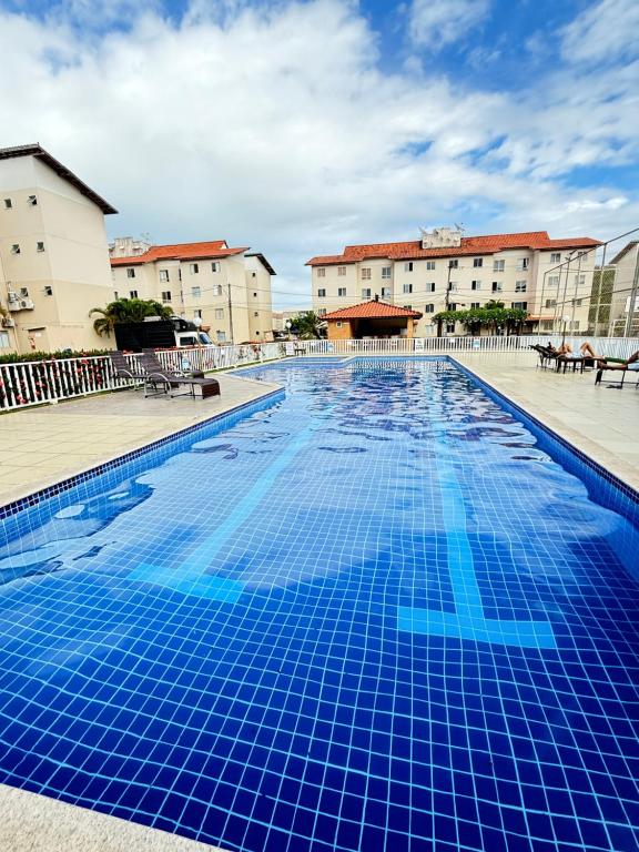 a large swimming pool with blue tiles in a building at Apartamento 100 metros da praia com piscina in Ilhéus