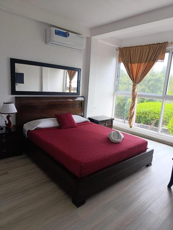 a bedroom with a large bed with a red blanket at Flightless Cormorant in Puerto Ayora