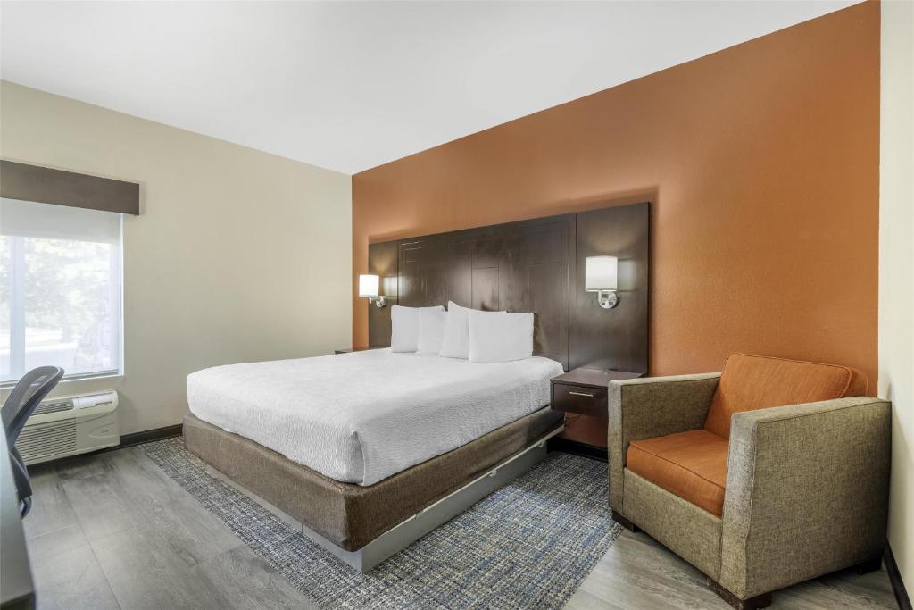 a hotel room with a bed and a chair at Best Western Plus Lee's Summit Hotel & Suites in Lees Summit