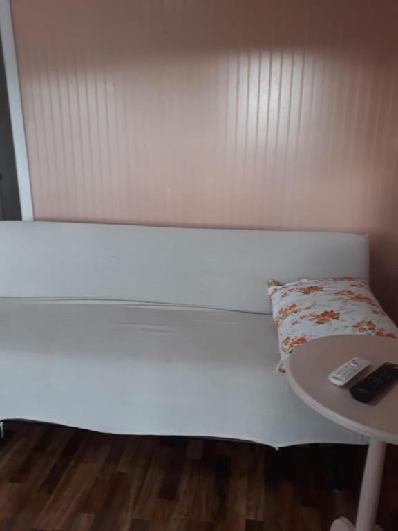 a white bed with a table and a remote control at Cabañas la doña in Aytuy