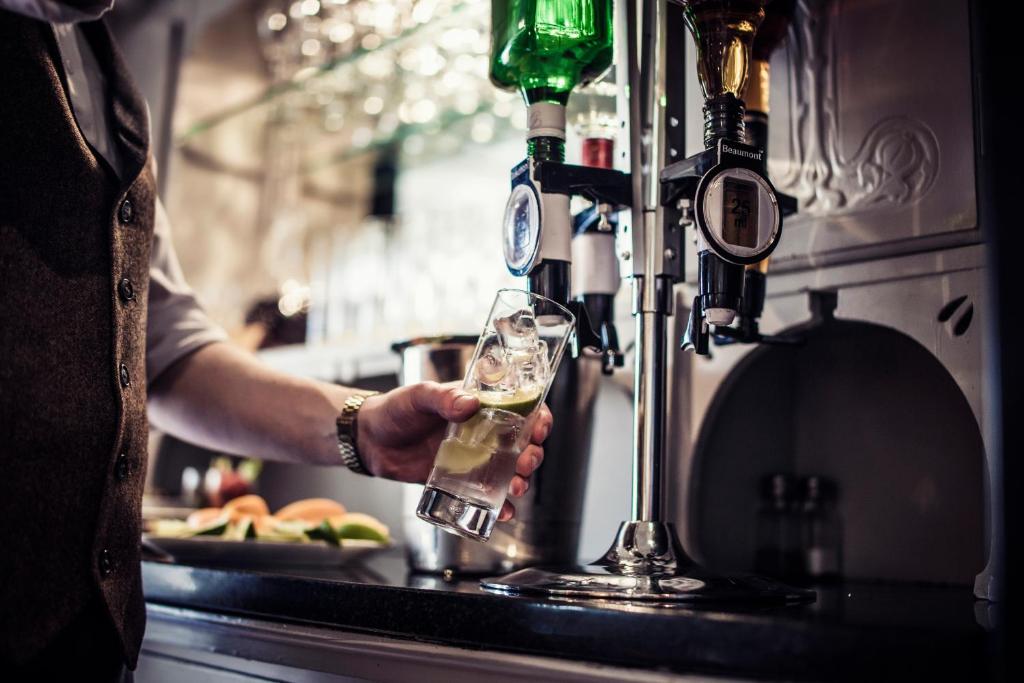 a man is holding a glass of wine in a bar at Carlton George Hotel in Glasgow
