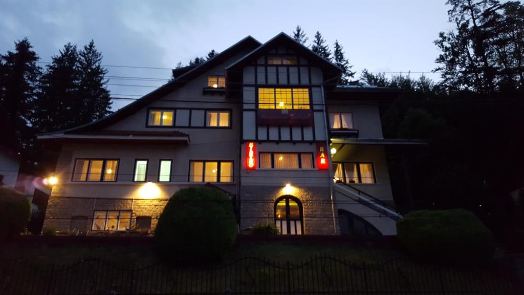 una casa iluminada por la noche con luces encendidas en Pensiunea Vila Gabriel en Sinaia