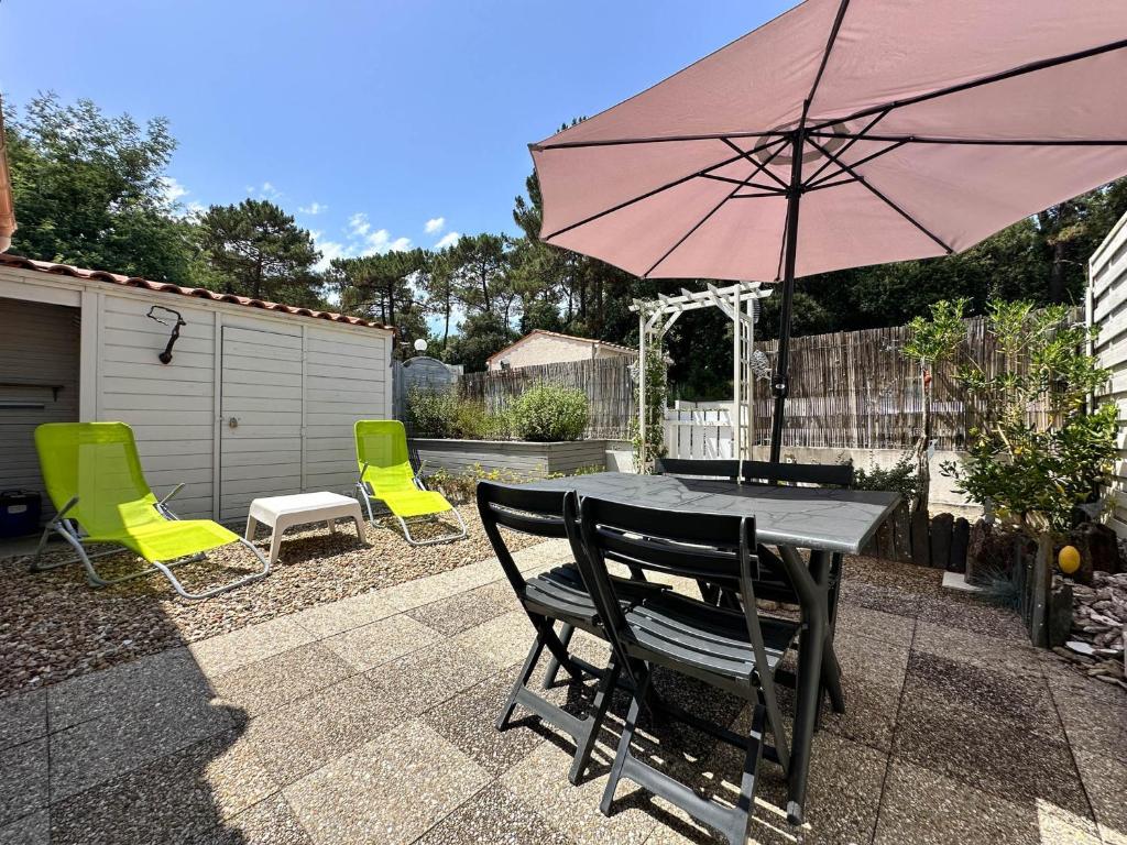 un patio avec une table, des chaises et un parasol dans l'établissement Maison rénovée pour 4 pers, proche plage/la mer, WIFI, BBQ, parking, calme près pistes cyclables - FR-1-705-18, à La Palmyre