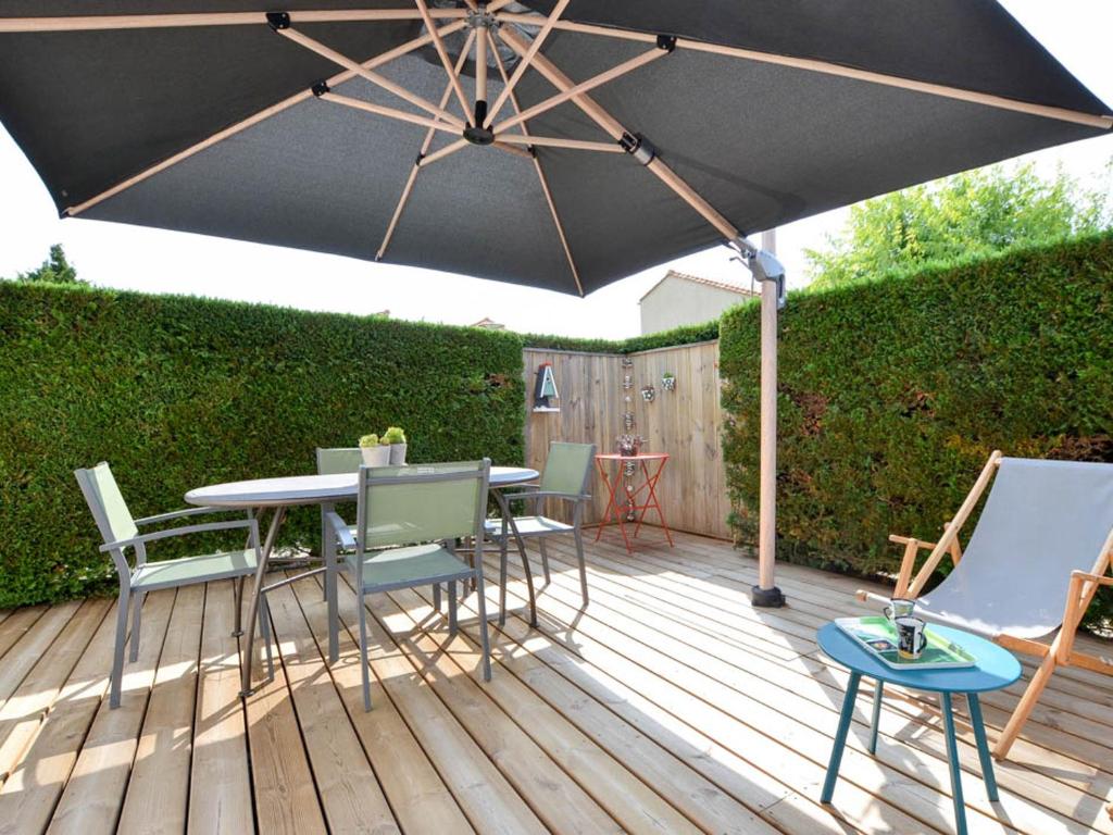 un patio avec une table, des chaises et un parasol dans l'établissement Maison Ravissante 4/5 pers, Jardin Privatif, Parking, Résidence Piscine - FR-1-705-4, à La Palmyre