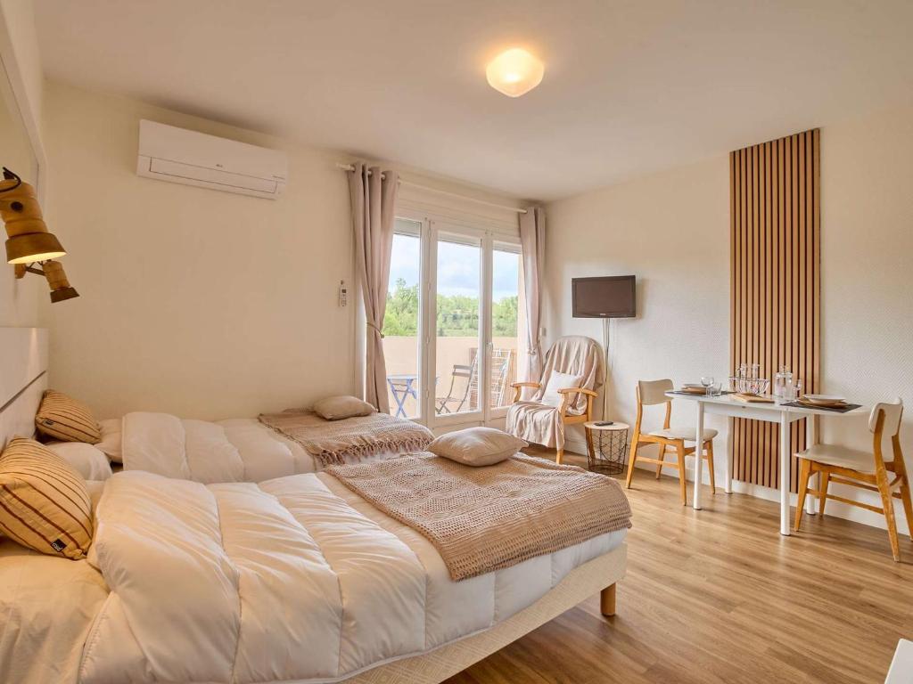 una camera da letto con due letti, un tavolo e delle sedie di Studio rénové et climatisé avec balcon pour 2 personnes - FR-1-841-24 a Barbotan-les-Thermes