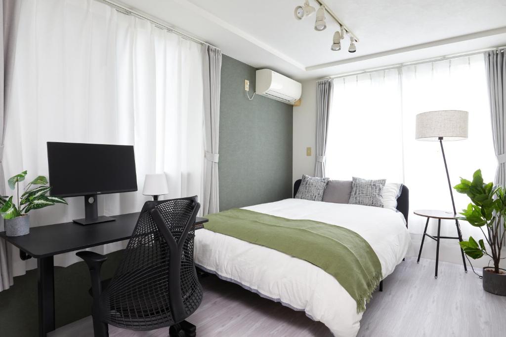 a bedroom with a bed and a desk with a computer at Shirogane Apartment in Tokyo