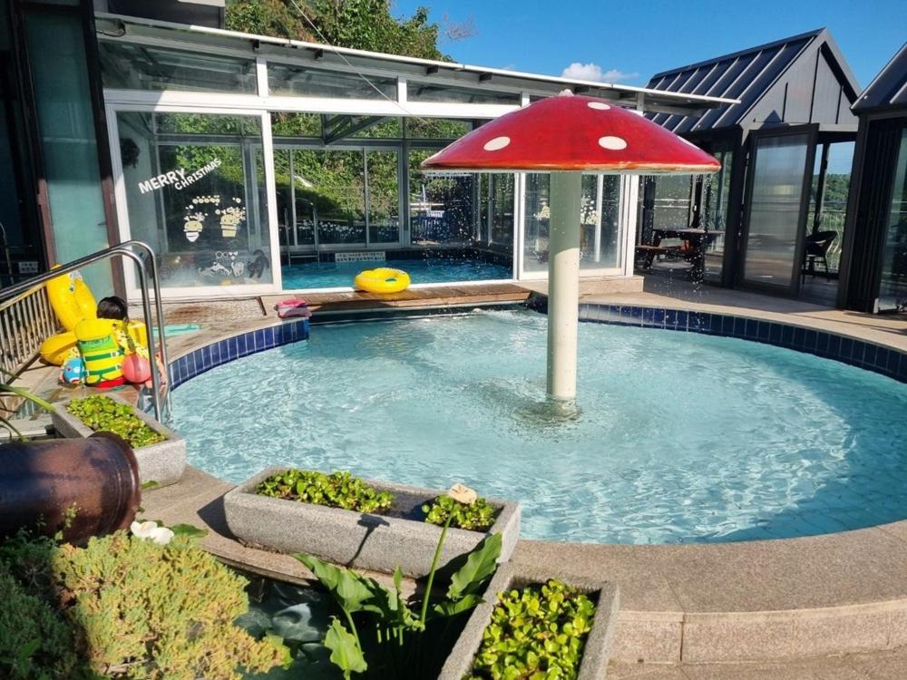 a small pool with a red umbrella in it at Yangpyeong Blue Hill Pension in Yangpyeong
