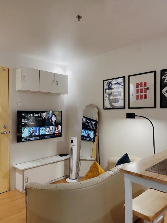a living room with a couch and a tv on the wall at Cozy 2BR Condo Near Davao Airport with Samal View in Davao City