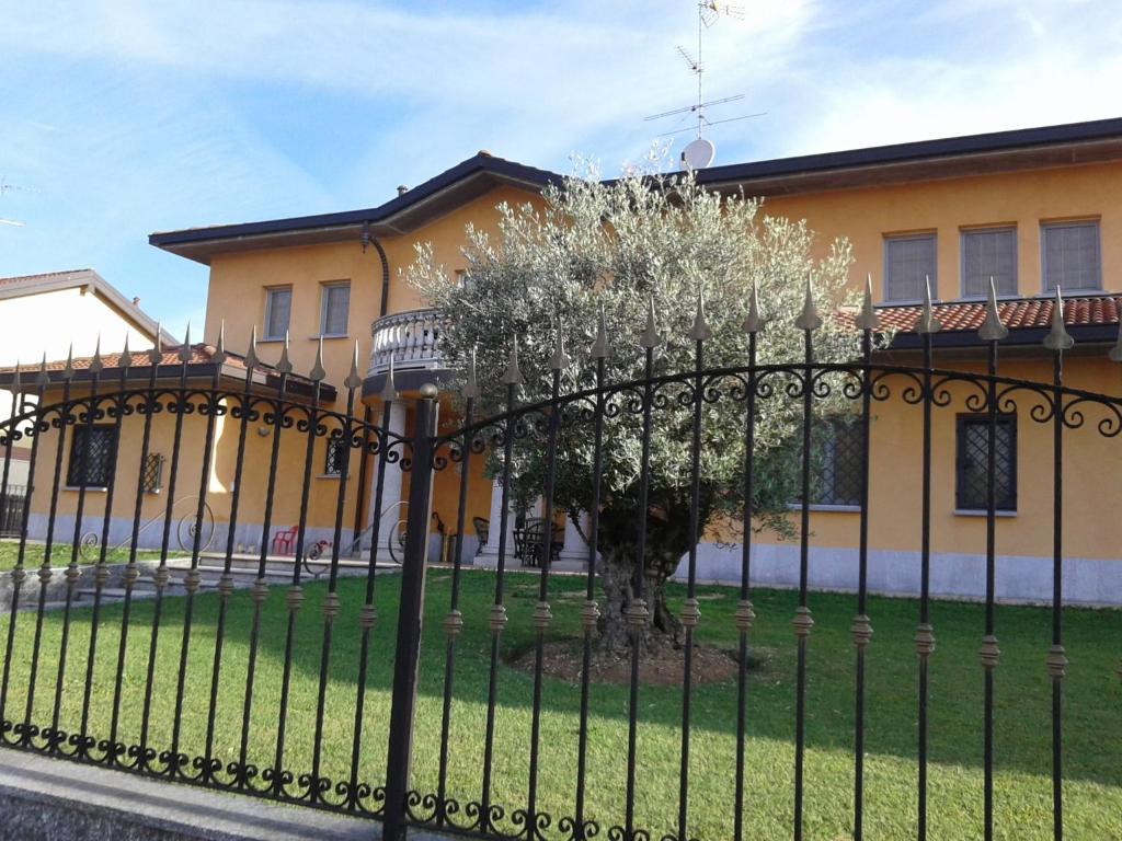 a black fence in front of a house with a tree at One M in Borgarello