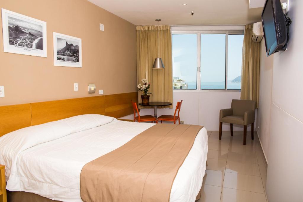 a hotel room with a bed and a table and a window at Atlantis Copacabana Hotel in Rio de Janeiro