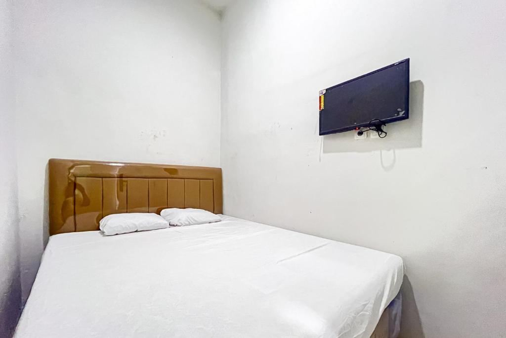 a bedroom with a bed and a flat screen tv at Guest House 21 RedPartner in Jakarta