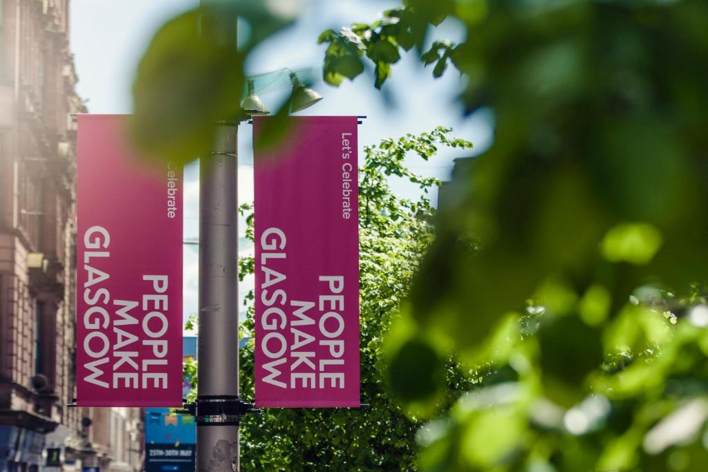 two pink banners on a pole on a street at Carlton George Hotel in Glasgow
