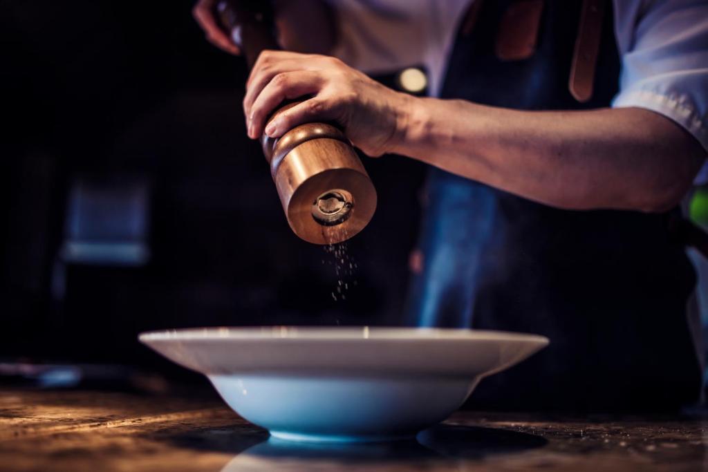 a man is sprinkling flour on a white bowl at Carlton George Hotel in Glasgow