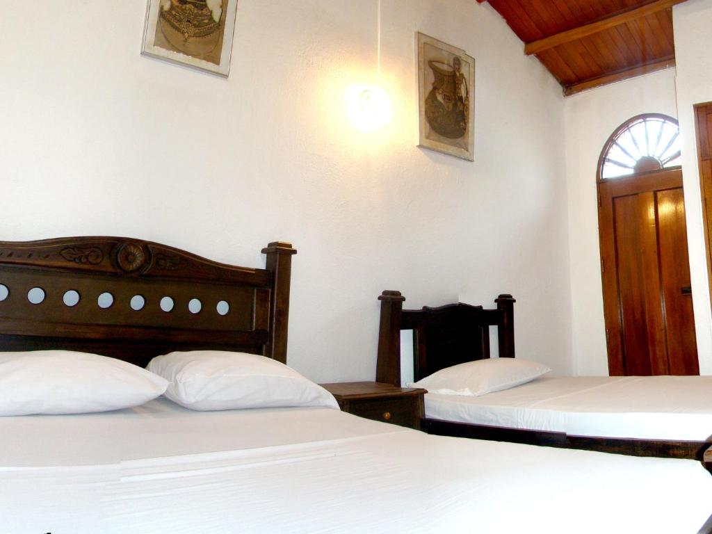 a bedroom with two beds and a window at Hotel Casa Vieja in Santa Marta