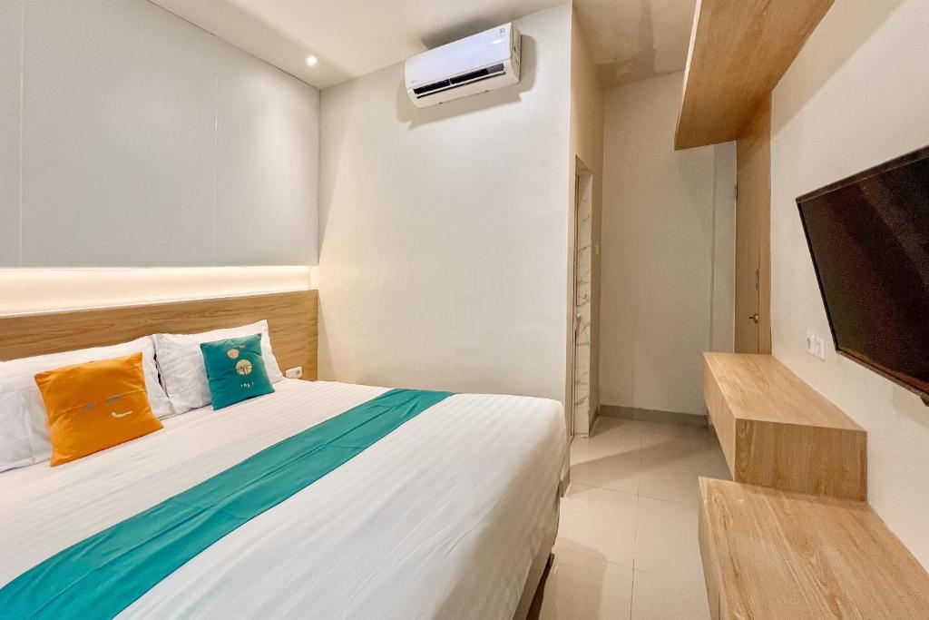 ein Schlafzimmer mit einem Bett und einem Flachbildfernseher in der Unterkunft Sans Vibes Millennium Garden Medan in Pulauberayan