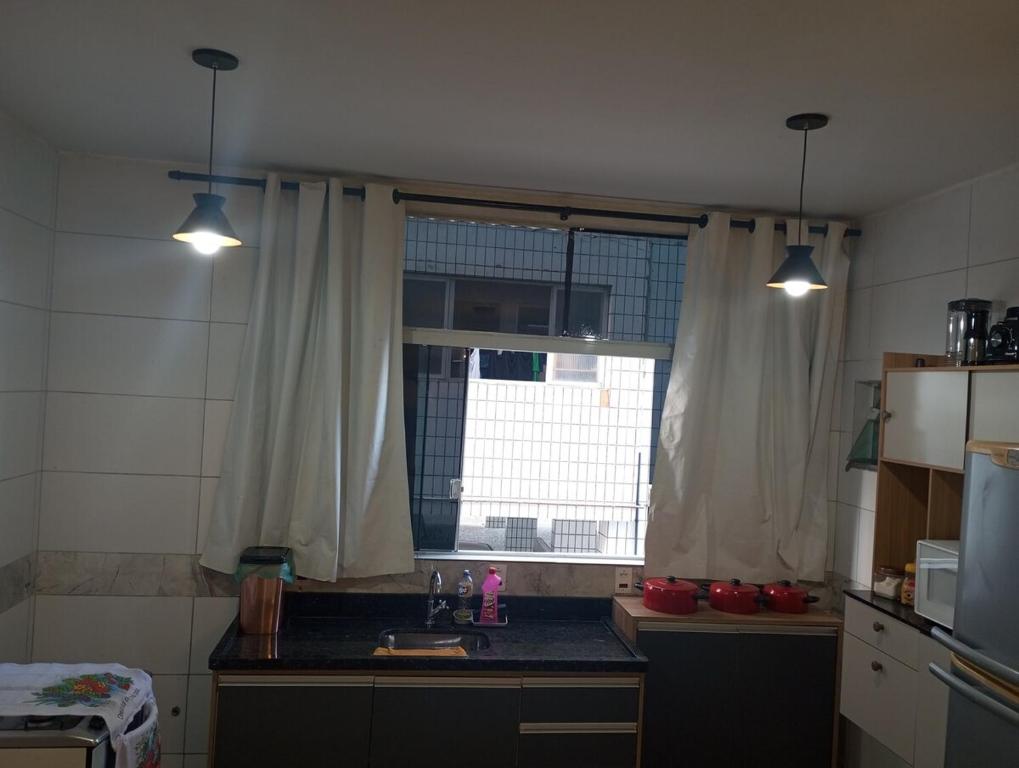 a kitchen with a sink and a window with two lights at Kitnet pé na areia in Praia Grande