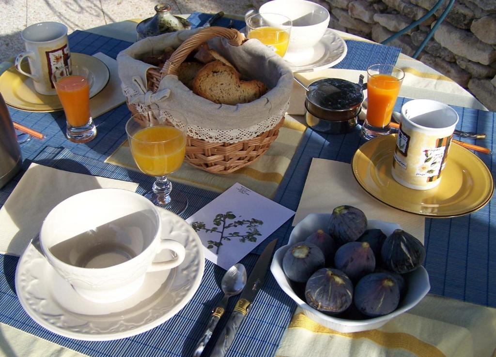 un tavolo con piatti e tazze e un cesto di cibo di Le Verger a Gordes