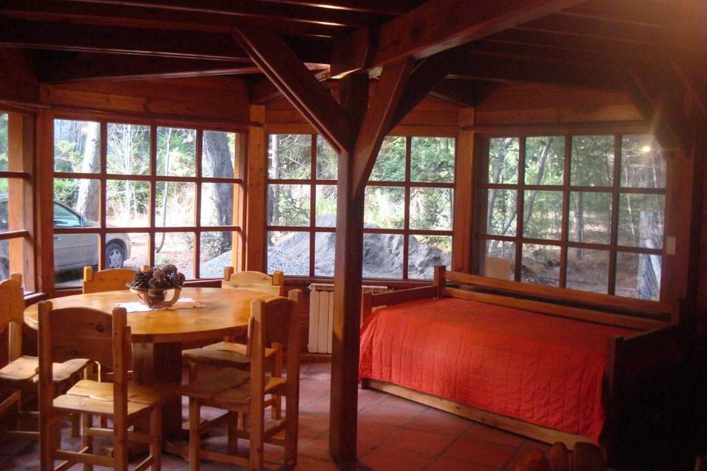 1 dormitorio con 1 cama, mesa y sillas en Cabañas Lucero del Bosque en San Carlos de Bariloche