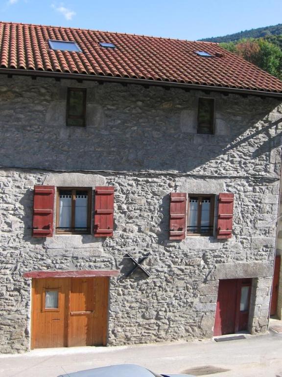 a stone building with red shuttered windows on it at Larraenea Bed and Breakfast in Lesaka