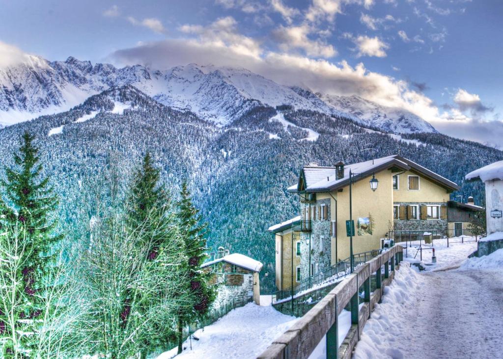 a house in the snow with mountains in the background at Albergo Eden in Ponte di Legno