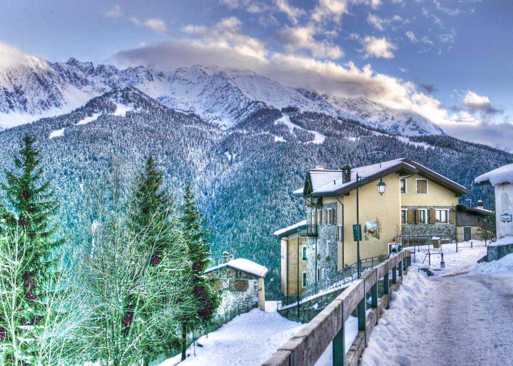 una casa nella neve con montagne sullo sfondo di Albergo Eden a Ponte di Legno