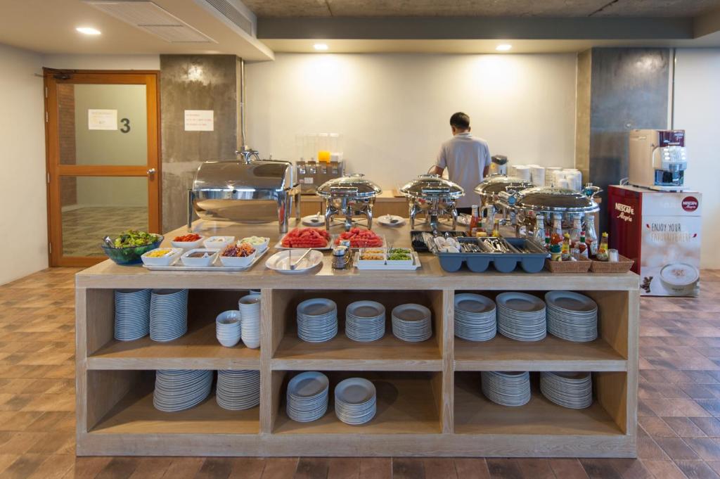 a food counter with plates and a man in a kitchen at The Sixteenth Naiyang Beach Hotel SHA Plus in Nai Yang Beach