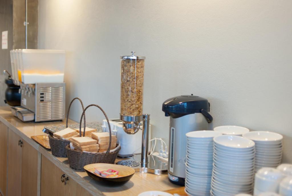 a kitchen counter with plates and cups and a mixer at The Sixteenth Naiyang Beach Hotel SHA Plus in Nai Yang Beach