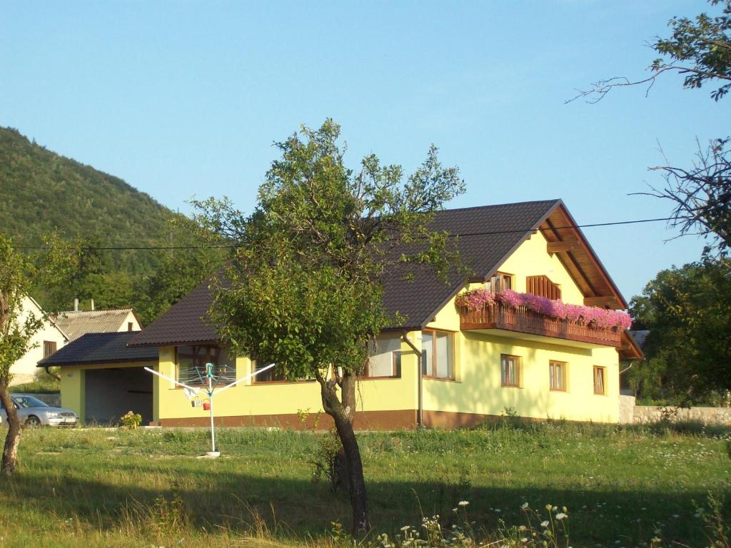 Una casa amarilla con un árbol delante. en House Mara, en Korenica