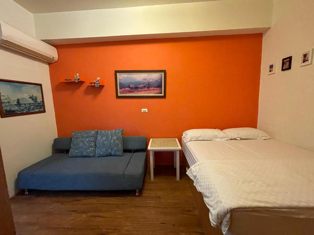 two beds in a room with an orange wall at Sunshine Guest House in Hualien City