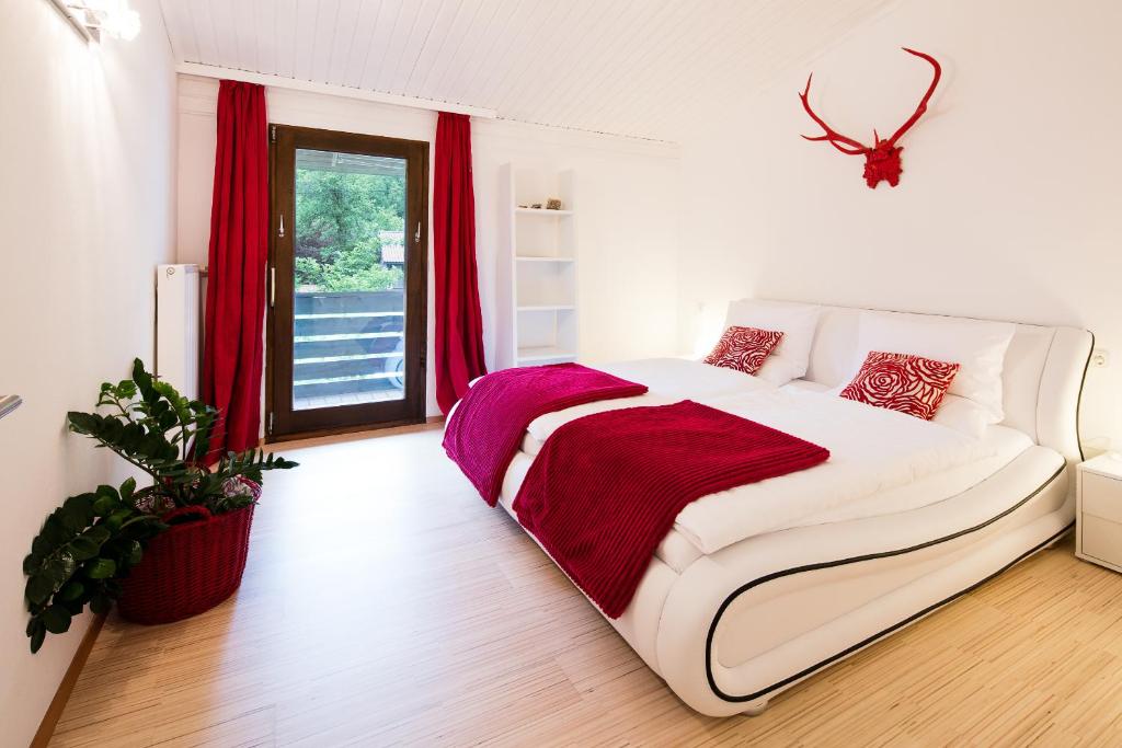 białe łóżko w pokoju z czerwonymi zasłonami w obiekcie W & S Executive Apartments - Hallstatt I w Hallstatt