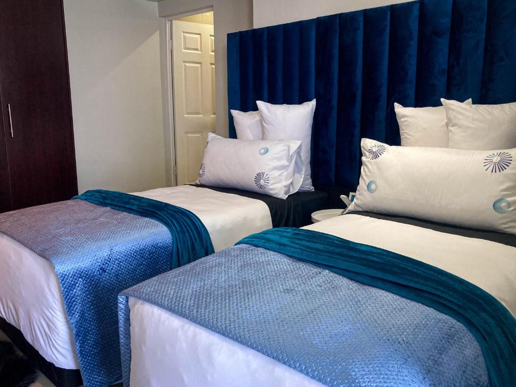 een kamer met 2 bedden met blauwe en witte kussens bij AA Sea View in Durban
