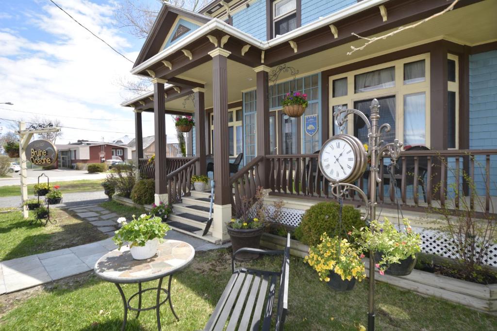 ein Haus mit einer Uhr auf der Veranda in der Unterkunft Auberge Bruine Océane in Matane